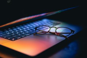 close up laptop keyboard colorful neon illumination eyeglasses